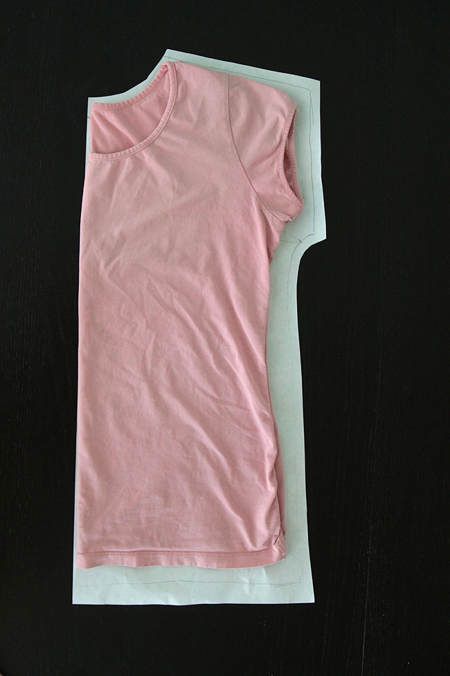 Pink t-shirt folded on paper, traced around to create a pattern