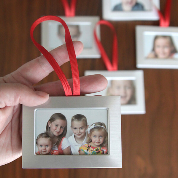 hand holding small silver frame with photo of kids in it and red ribbon loop