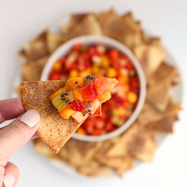 Hand holding chip with fruit salsa on it.
