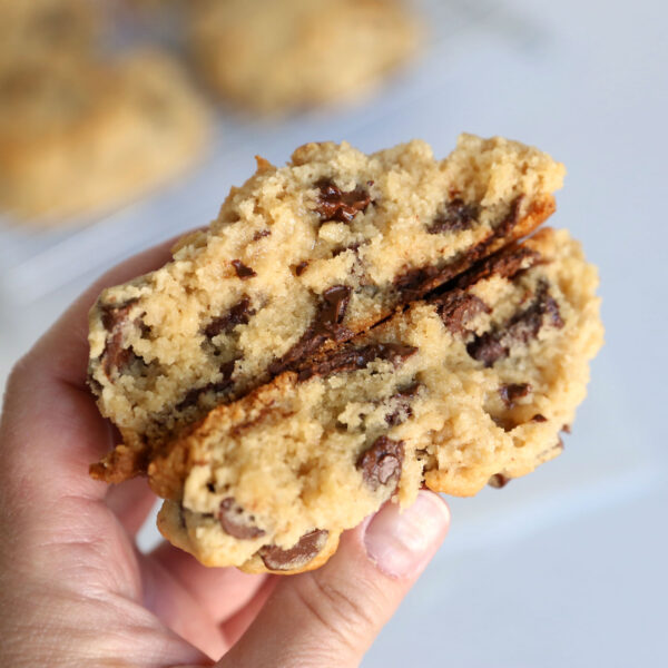 Thick chocolate chip cookie broken in half with melty chocolate and gooey center.