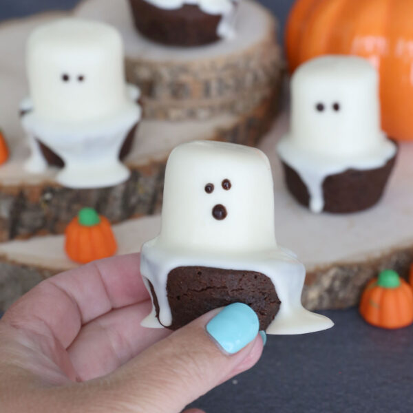 Hand holding brownie bite ghosts.