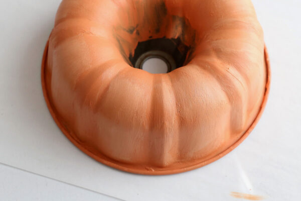 Bundt pan with second coat of paint including lighter colored paint on some areas.