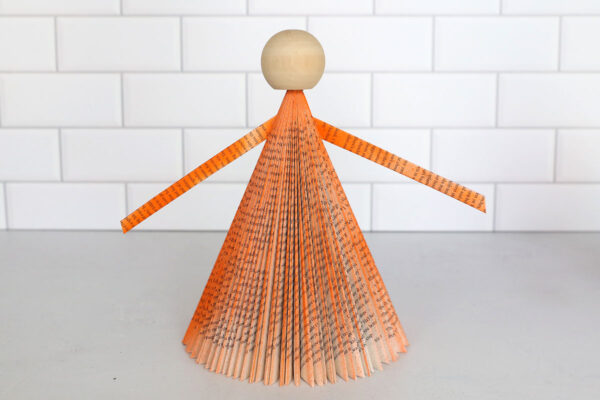 Book cone with wood ball glued on top for head; arms glued on.